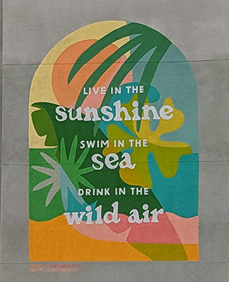 Colorful mural that reads, "Live in the Sunshine, swim in the sea, drink in the wild air"