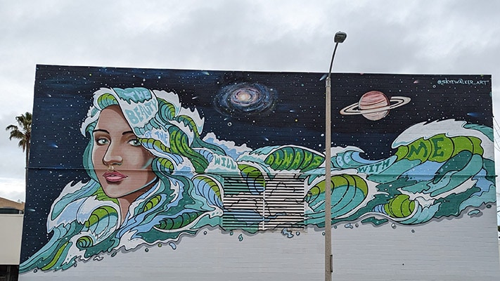 Wall mural of a woman with ocean waves for hair and text reading "The Beauty of the Sea will Always Be with Me."