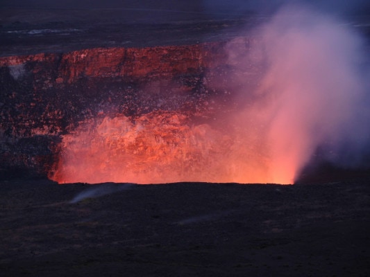 Lava glows against the night sky in a crater in Hawai'i Volcanoes National Park