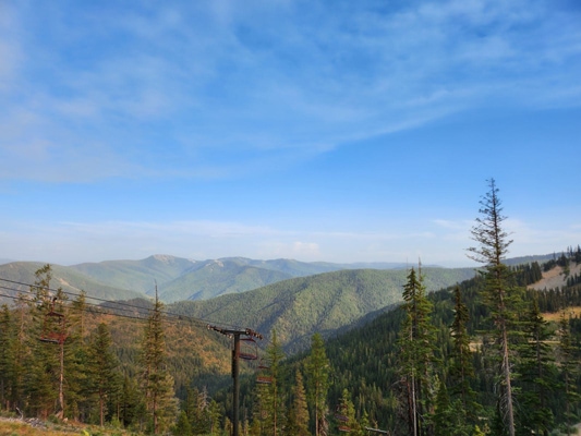 Green mountains fade away into the distance with blue skies and wispy white clouds above