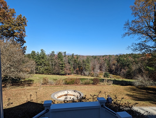 View of the sky, trees , and mountains, and an empty cement pond