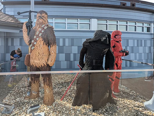 Life-size figures of Chewbacca, Kylo Ren, and a red Sith trooper from Star Wars made out of Legos