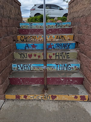 A colorful set of stairs with a quote on the risers. The paint is a little damaged so all that can be read is "If you...garden and a library you have everything...Cicero"