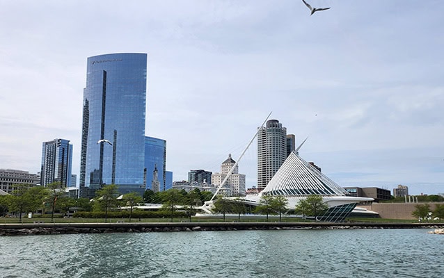 A relatively low white building appears to sail on Lake Michigan. A few skyscrapers rise in the background